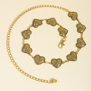 Detailed macro view of vintage gold metal heart-shaped chain belt with bohemian floral patterns