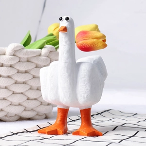 Close-up of a white resin duck figurine with orange beak and textured surface details