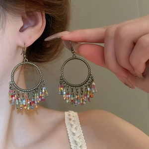 Detail of bohemian hoop earrings with colorful beaded tassels shown on a model
