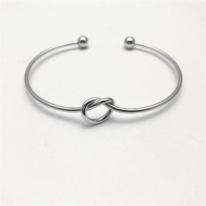 Minimalist silver open cuff bracelet with knot design and round beads on white background