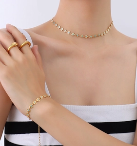 Detailed close-up of golden necklace and bracelet set featuring light blue enamel flowers
