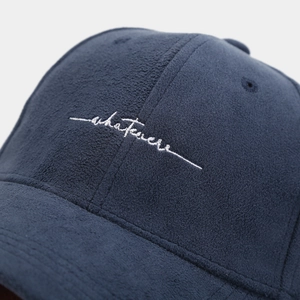 Close-up of white 'whatever' embroidery on a navy blue fleece baseball cap detail