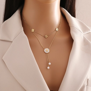 Gold double-layered necklace with clover charms and pearl tassel on a model