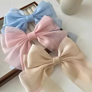 Elegant organza bow hair clips in blue, pink and champagne colors on a wooden tray