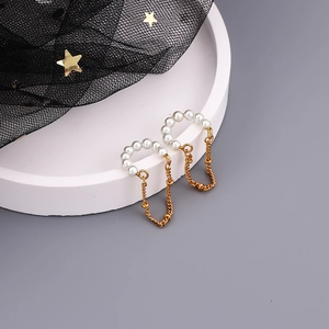 Detail of gold-plated pearl chain earrings with delicate tassels on a decorative tray