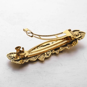 Nahaufnahme der goldenen Vintage-Haarspange mit Fokus auf den Federverschluss-Mechanismus