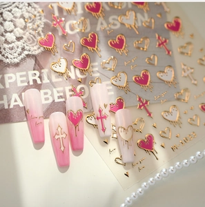 Detail of M-1033 nail decals featuring gold heart and cross designs on pink nails