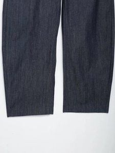 Dettaglio dell'orlo a taglio vivo su jeans blu scuro che mostra la trama del denim