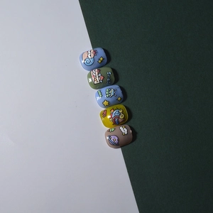 Detailed close-up of cute cartoon snail and space themed press-on nails for kids