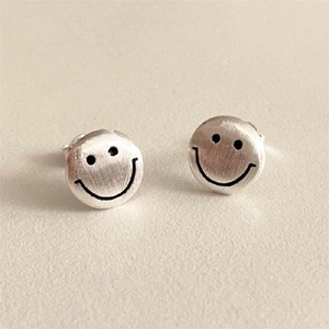 Macro shot of 925 sterling silver smiley face stud earrings with brushed metal finish