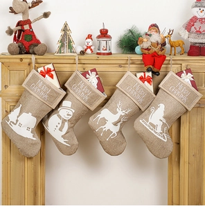 Detail of four linen Christmas stockings with reindeer and snowman patterns on fireplace