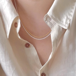 Detail of minimalist gold and silver twisted rope necklaces worn together on model