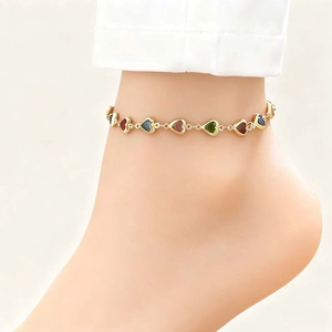 Close-up of heart-shaped anklet with colorful charms on a golden chain for women