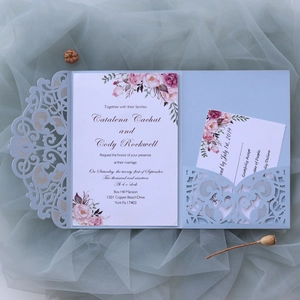 Macro view of blue laser-cut wedding invitation set with floral watercolor patterns