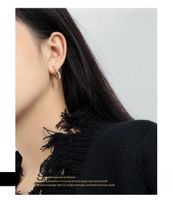 Macro detail of irregular S925 sterling silver U-shaped hoop earring on model