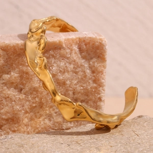 Detail of 18K gold-plated irregular wave cuff bracelet on textured natural stones
