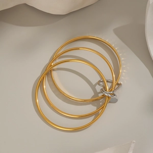 Macro shot of triple-layer interlocked 18K gold and silver bangles with heart charm