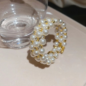 Detail view of triple-layer pearl bracelet with gold rhinestone spacers on a glass