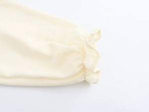 Detail shot of ruffled elastic cuffs on a cream French square neck dress fabric