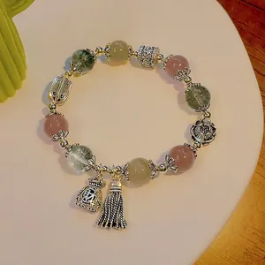 Retro ethnic agate bracelet with silver fortune pouch charm and tassels on white plate