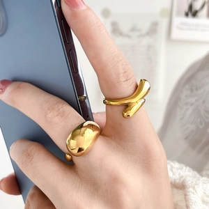 Polished gold arched and crisscross open rings displayed on hand for women
