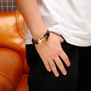 Men's nautical black leather bracelet with golden anchor clasp worn on the wrist