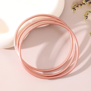 Dettaglio di bracciali in resina rosa glitterata con foglia d'oro su sfondo viola estetico