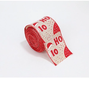 Detail of Christmas ribbon with Ho Ho Ho print and red Santa hat pattern on faux linen