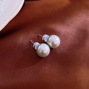 Detail of elegant white round pearl stud earring on brown satin fabric background