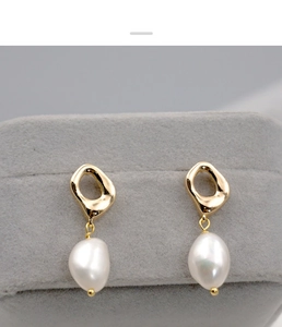Macro shot of French baroque pearl earrings with gold metal squares in a gray jewelry box