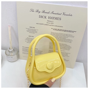 Detailed close-up of a mini yellow jelly bag with a sleek gold chain on a vintage backdrop