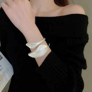 Close-up of matte silver leaf-shaped open cuff bracelet worn on a female wrist
