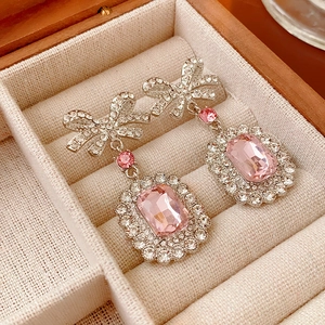 Détail de boucles d'oreilles nœud en argent avec pierres roses rectangulaires et zircon