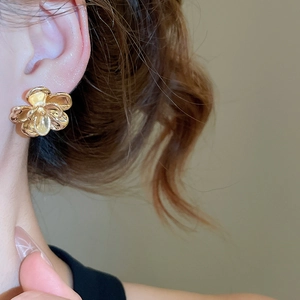 Close-up of a model wearing the elegant golden flower stud earring with a glossy finish