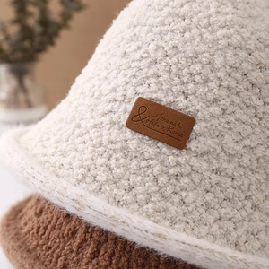 Chic cream-colored fleece bucket hat for women featuring a vintage leather label detail