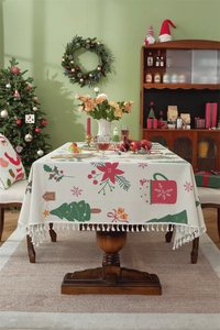 Detailed view of beige Christmas tablecloth featuring red floral patterns and white tassels