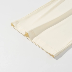 Dettaglio dell'orlo dei pantaloni in maglia color crema con cuciture di alta qualità