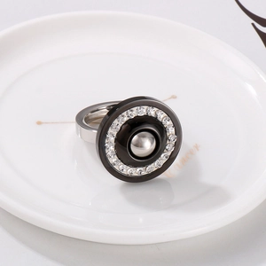 Macro shot of silver zircon ring with black circular inlay and crystal halo on ceramic tray