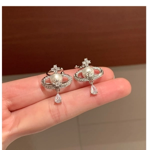 Detailed close-up of silver Saturn pearl clip earrings with sparkling cubic zirconia