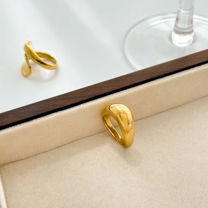 Minimalist thick irregular golden arc rings on a beige velvet jewelry tray