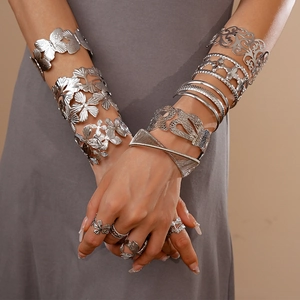Detail of silver ginkgo leaf and butterfly bangles layered with metal mesh rings