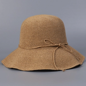 Detail of hand-woven khaki straw hat showing crochet texture and bow decoration