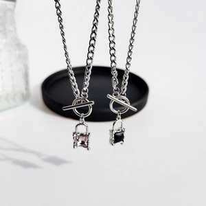 Detailed view of silver lock pendant necklaces with OT buckle and square pink and black gems
