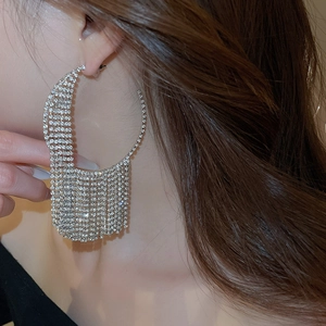 Close-up of sparkling rhinestone tassel earrings with geometric circular design on model