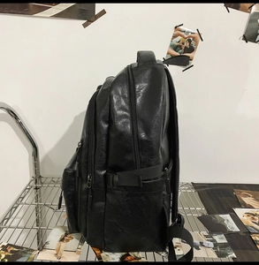 Vista laterale dello zaino in pelle PU nera con texture, tasche e fibbie regolabili