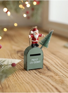 Detail of red Santa mailbox ornament with mini pine tree on a rustic wooden surface