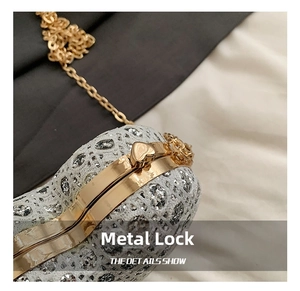 Detail of a sparkling silver sequin evening bag featuring a golden heart-shaped metal clasp
