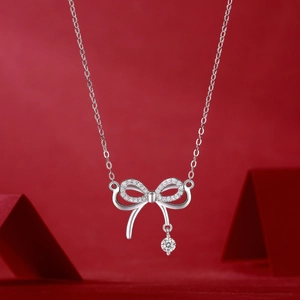 Close-up of S925 sterling silver bow pendant necklace with sparkling cubic zirconia on red