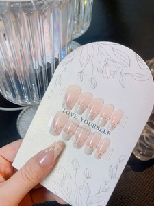 Detail of pink French V-tip press-on nails with pearl and gold bead accents