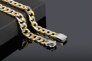 Macro view of gold and silver two-tone Cuban link bracelet on a premium jewelry box